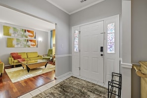 A living room with a yellow sofa, a coffee table, and a rug. There are two doors with stained glass windows and a small wooden chair.