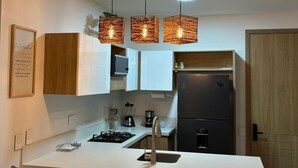 A modern kitchen with white cabinets, a black refrigerator, a stainless steel sink, and hanging pendant lights. - Espacioso y Confortable Bai Kristal (Cartagena de Indias)
