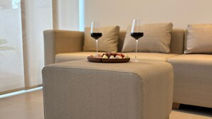 A modern living room with a beige sofa, a small ottoman with a fruit platter and two glasses of red wine. - Espacioso y Confortable Bai Kristal (Cartagena de Indias)