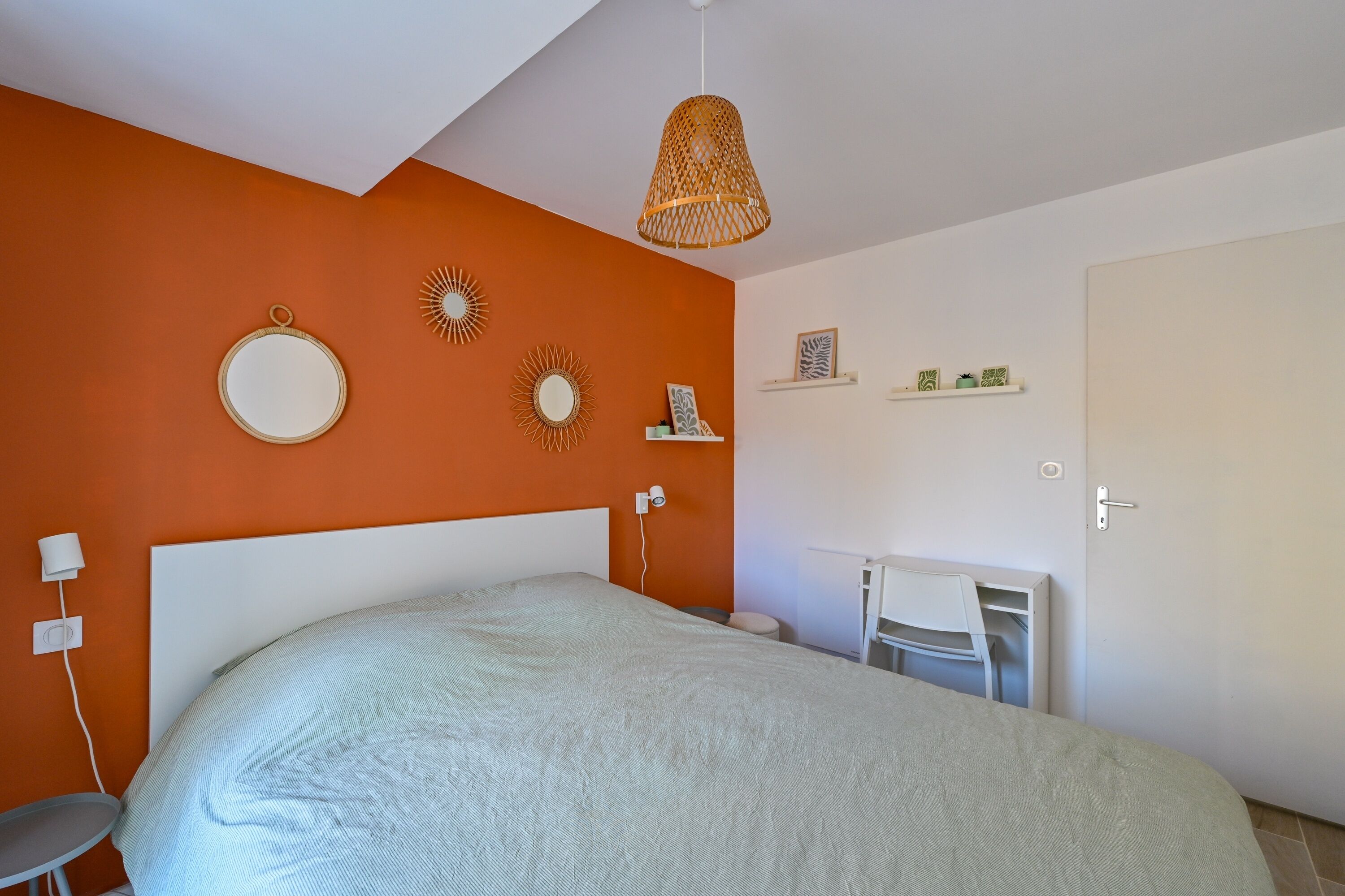 A bedroom with a large bed, a desk, and a chair.