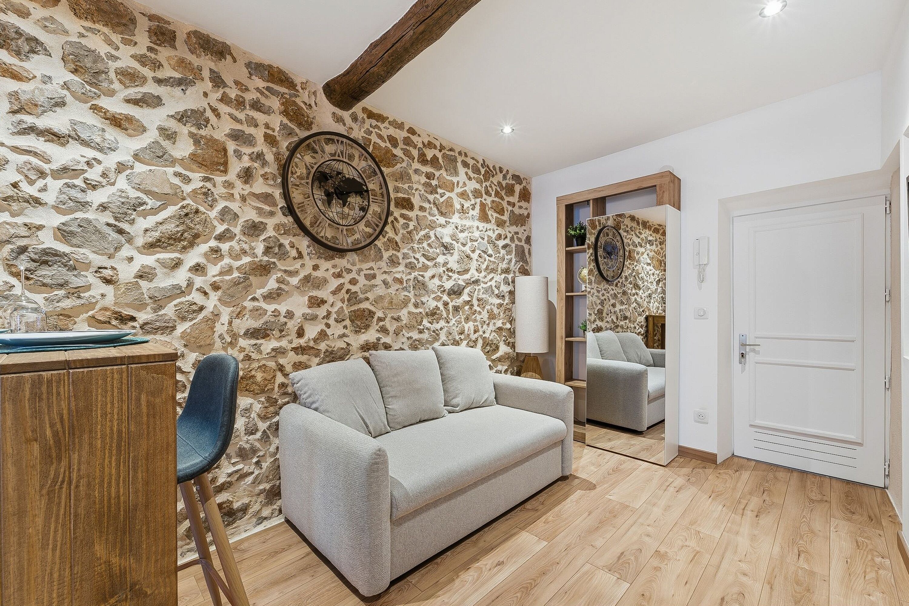 A living room with a stone wall, a sofa, a chair, and a wooden cabinet.