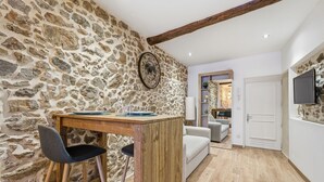 Een landelijke keuken met een stenen muur, houten barstoelen en een houten tafel.