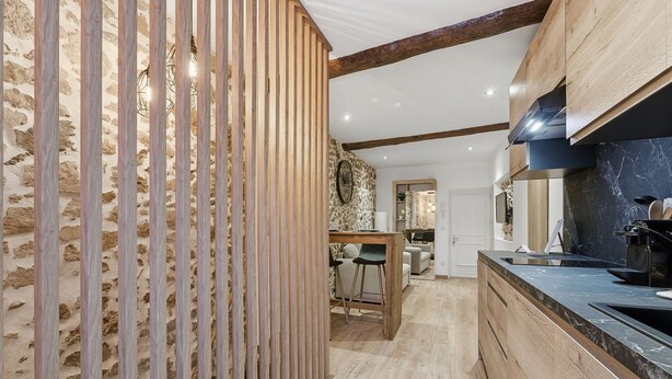 Een moderne keuken met houten details, een stenen muur en een marmeren aanrechtblad.