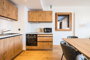 Eine moderne Küche mit Holzausstattung, einem eingebauten Ofen und einem Essbereich mit Holztisch und -stühlen.