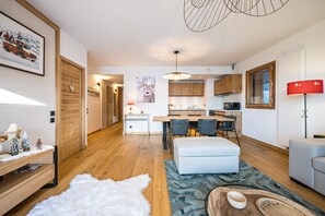 Ein modernes Wohnzimmer mit einem weißen Sofa, einem Essbereich mit einem Holztisch und einer Küche mit Holzschränken.