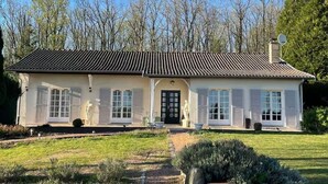 A two-story house with a tiled roof, white shutters, and a front door.
