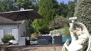 A patio area with outdoor furniture, a statue, and a house in the background.
