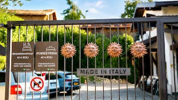 A gated entrance with signs for bed & breakfast and foresteria, a 'Made in Italy' sign, and a no dogs sign.