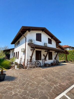 Um edifício de dois andares com fachada branca, vigas de madeira e varanda coberta.
