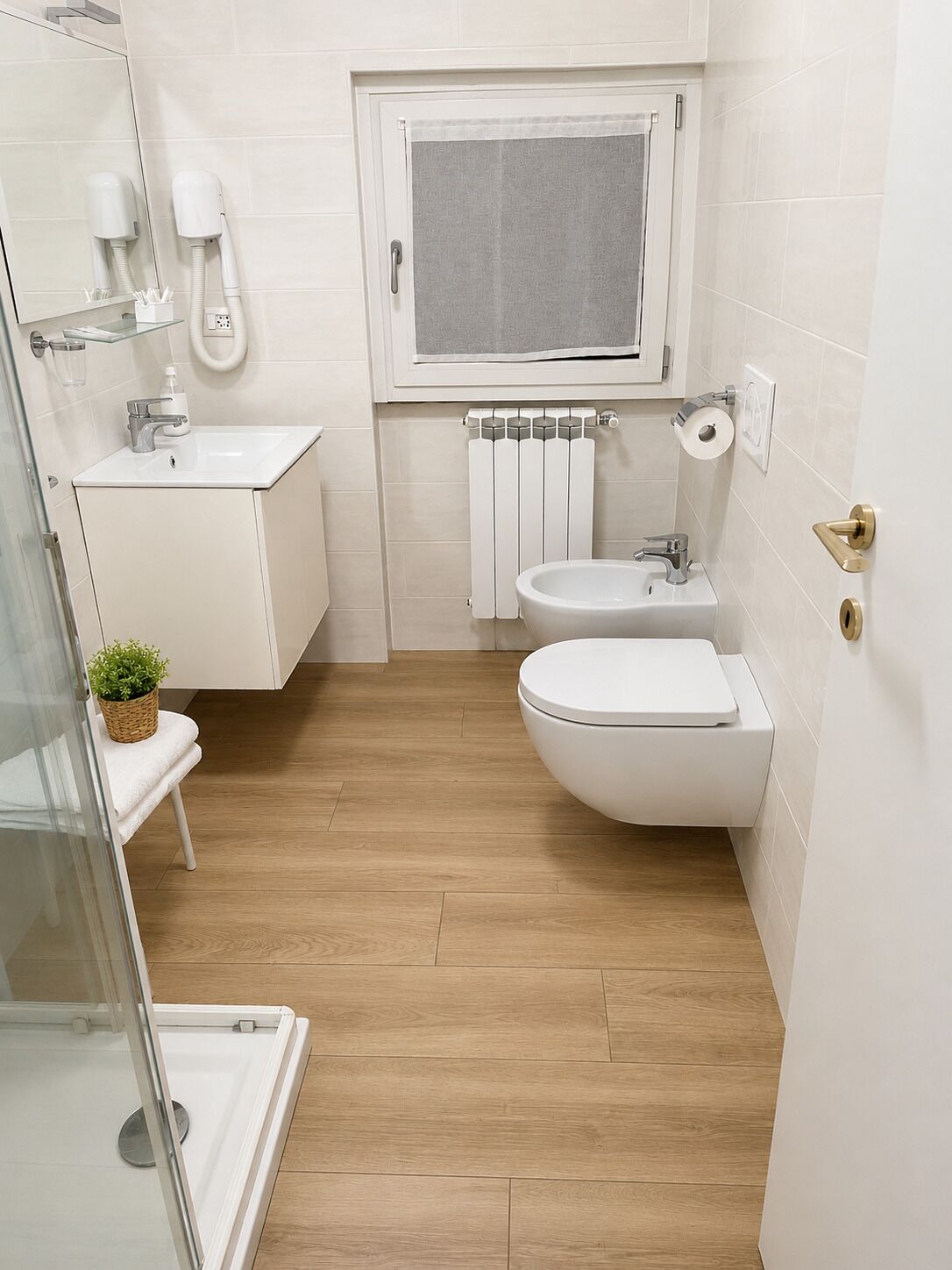 A modern bathroom with a toilet, bidet, and a glass shower enclosure.