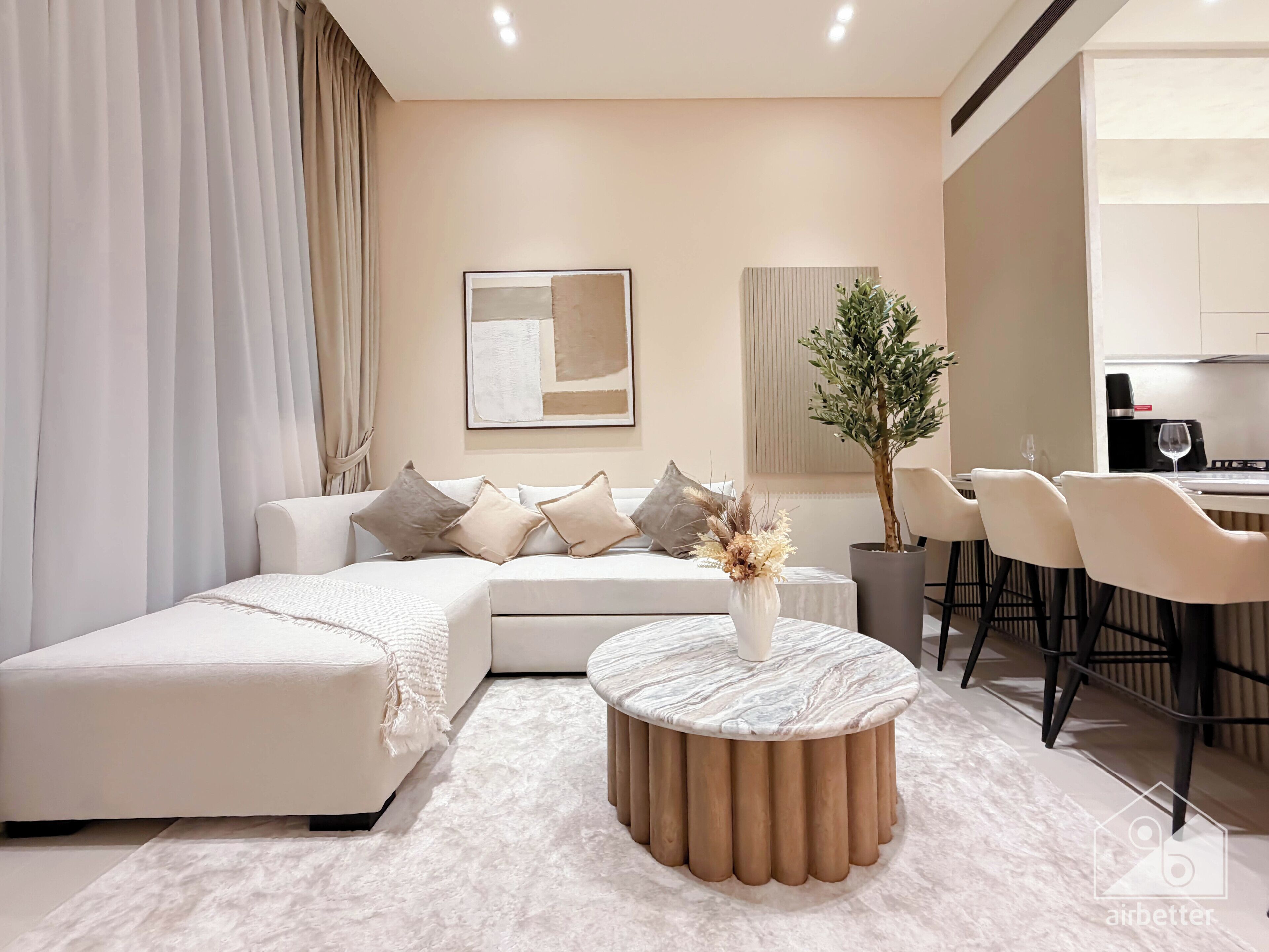 Un salon moderne comprenant un canapé, une table basse ronde et un coin repas avec des chaises et une table.