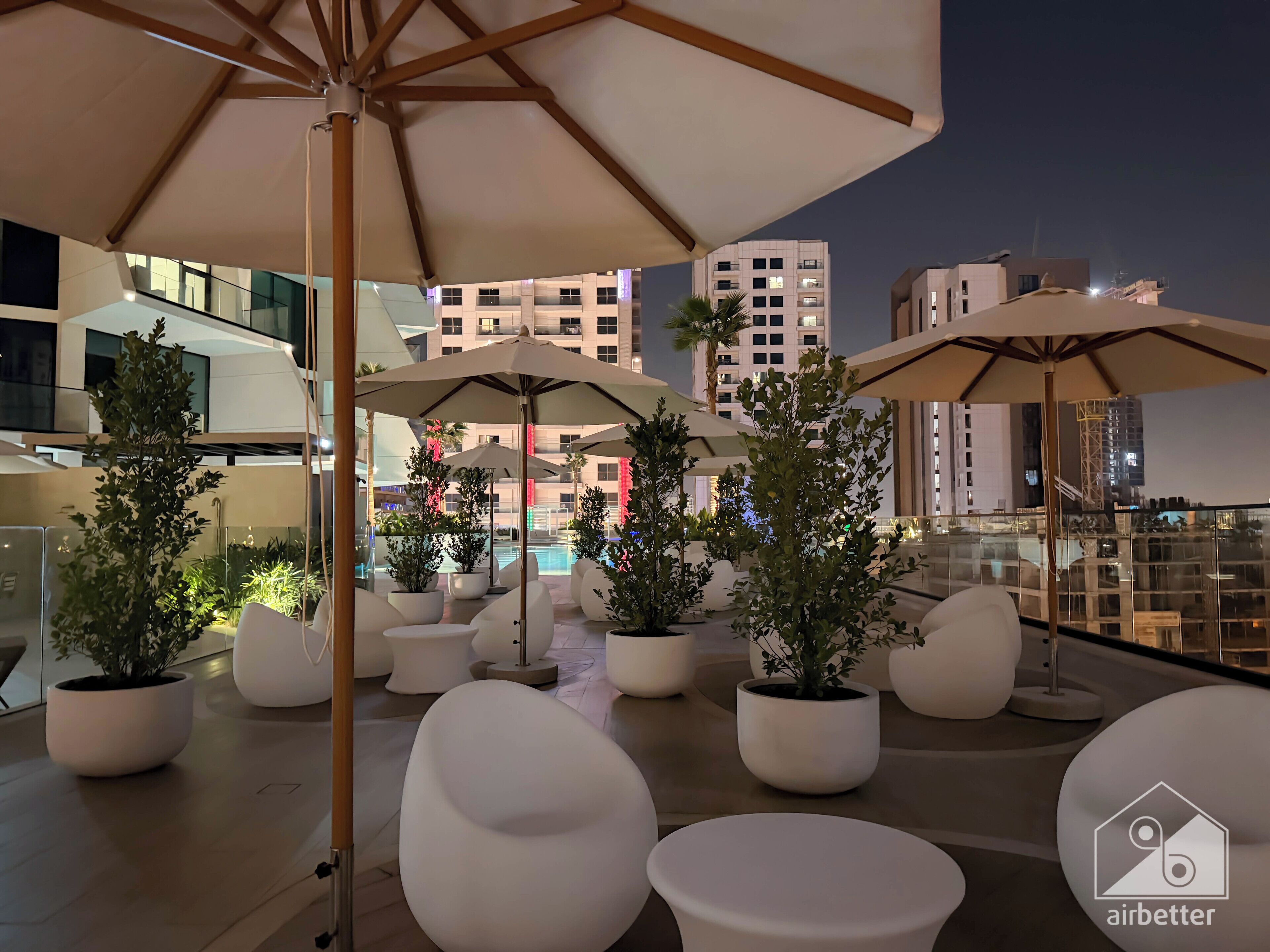 Une terrasse sur le toit, aménagée avec des espaces de détente en plein air, des parasols et des plantes en pot.