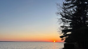 Ein Sonnenuntergang über ruhigem Wasser mit einer Holzsteg und einem Rasen.