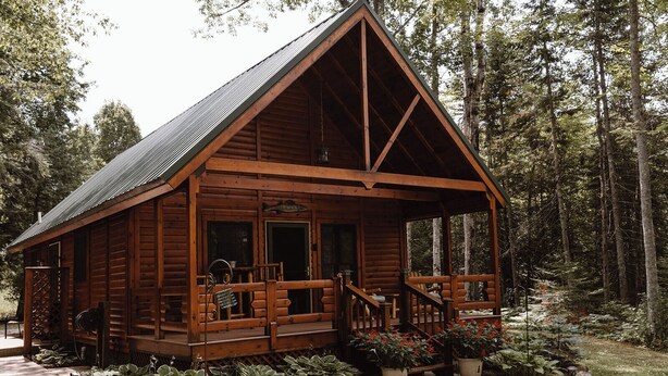 Eine Holzhütte mit Veranda, umgeben von einem Wald.