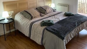 A bedroom with a wooden headboard, a bed with striped bedding, two bedside lamps, and three wall-mounted paintings. - Apartamento céntrico en Berga - ALBERGA (Berga)