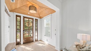 Un vestíbulo espacioso con techo de madera, puertas de cristal amplias y un tapete en el suelo.