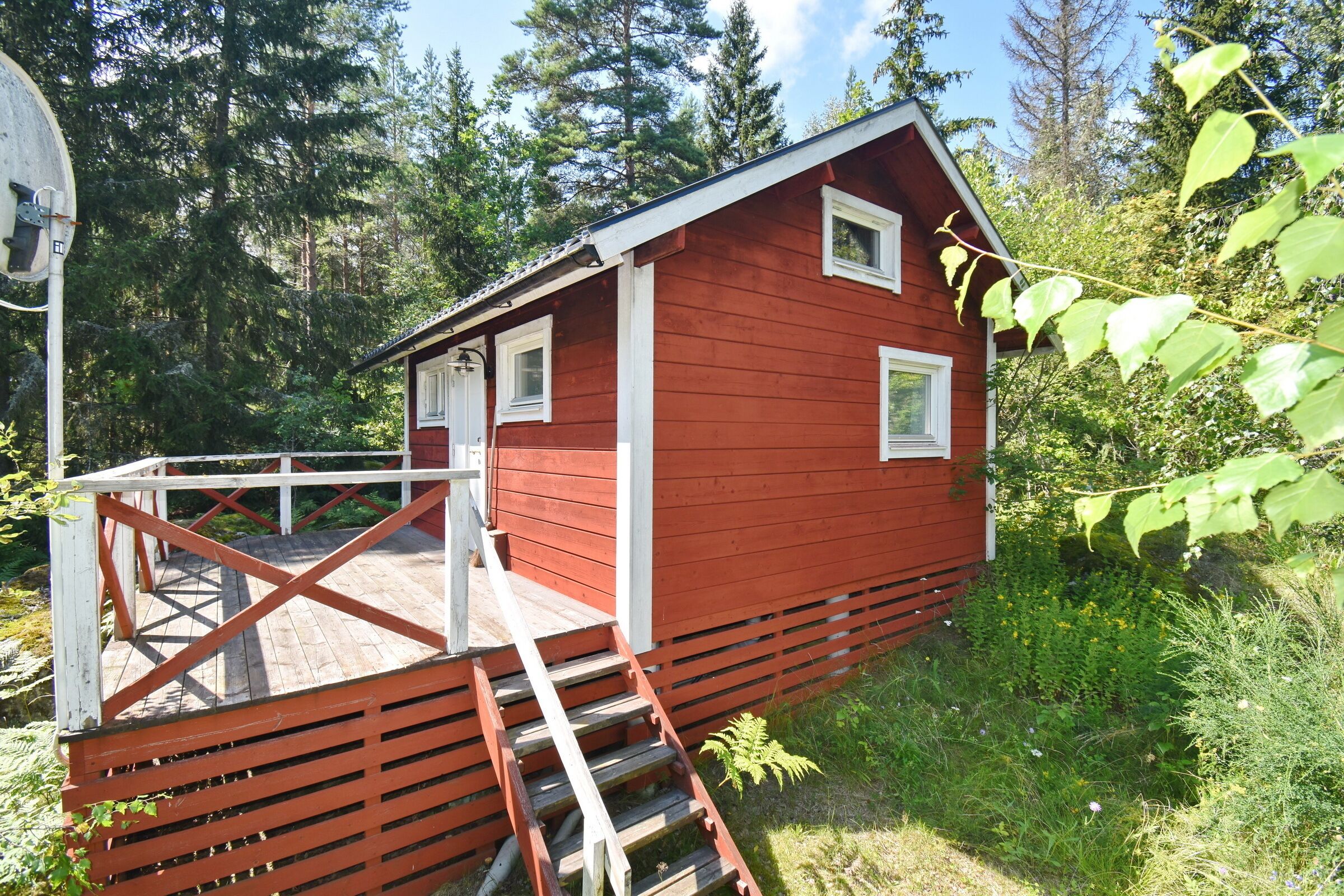 Eine rote Holzhütte mit einer kleinen Veranda und einer Leiter, die zum Eingang führt.