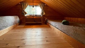 An attic bedroom with wooden slats, a window with curtains, and a bed.