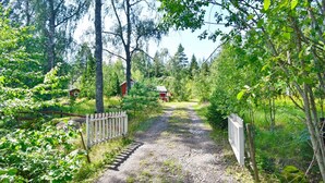 A gravel path leading to a red building surrounded by dense greenery and trees.