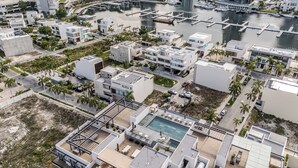 An aerial view of a modern residential area with a marina, featuring contemporary architecture, a rooftop pool, and a marina with boats. - Almare by Andiani Travel (Cancun)