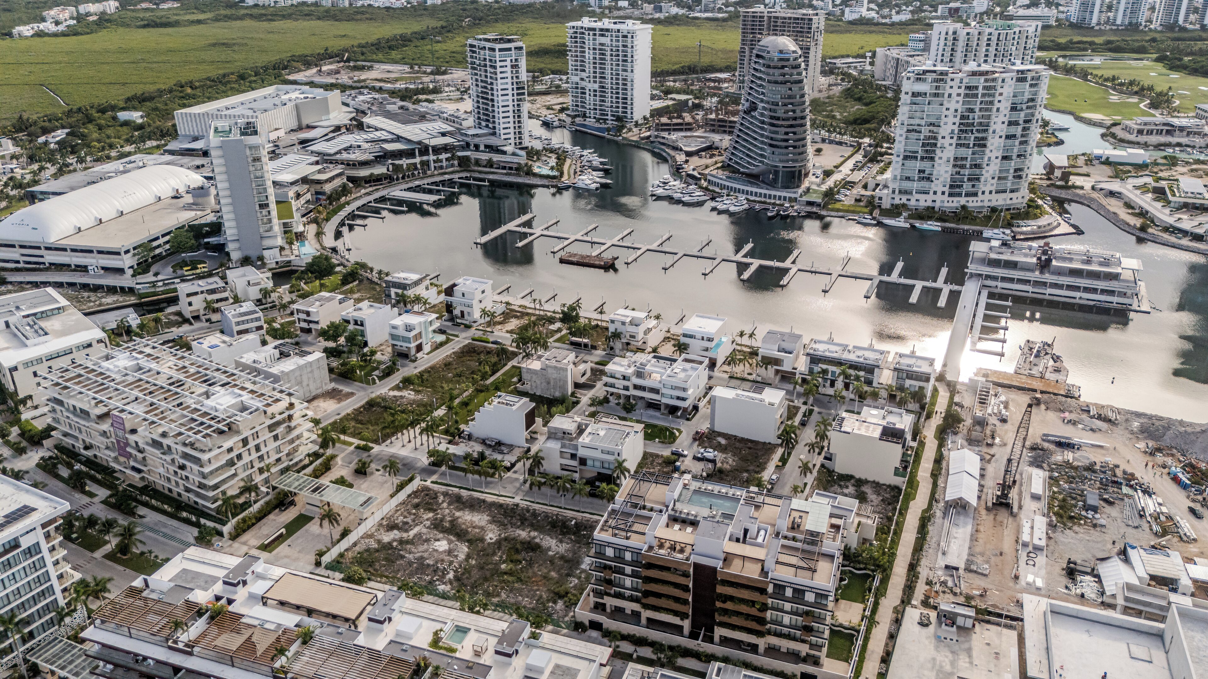 An aerial view of a modern urban area with high-rise buildings, a marina, and a river.