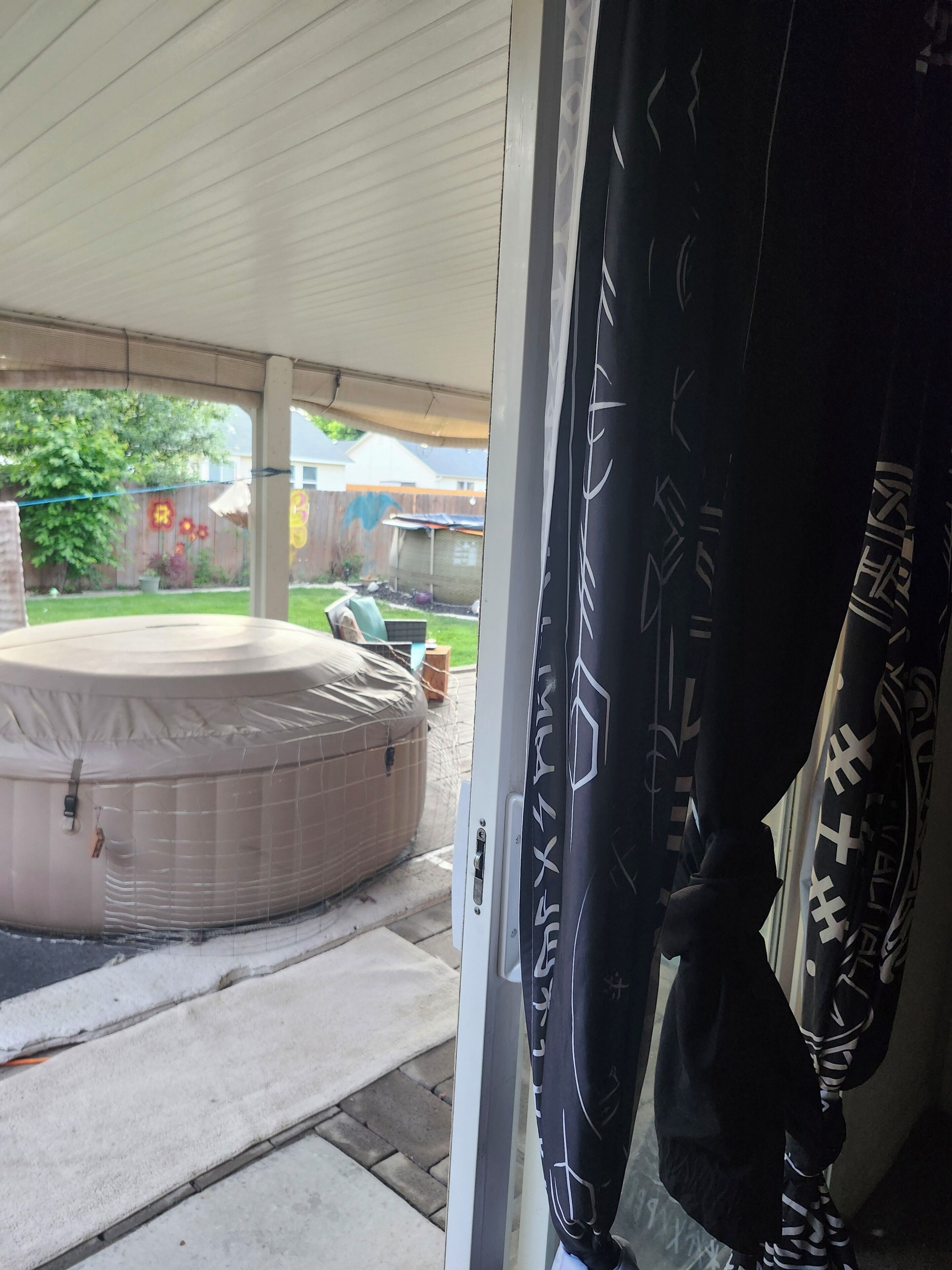 A covered patio area with a hot tub and a covered outdoor space.