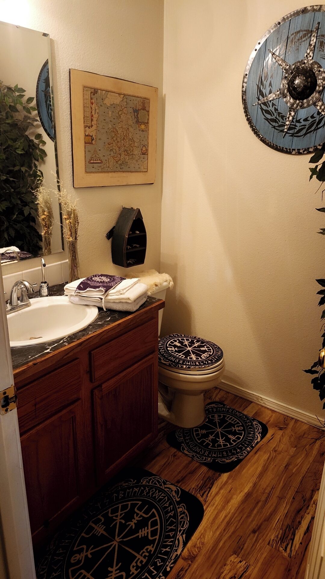 A bathroom with a wooden vanity, a sink, a toilet, and a map on the wall.