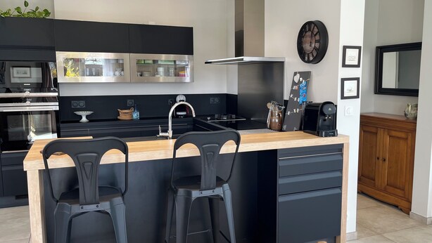 A modern kitchen with black cabinets, a wooden countertop, and a built-in stove.