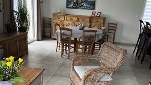 A dining area with a wooden table, wicker chairs, and a painting above the table.