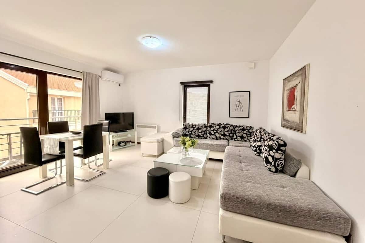 A modern living room with a sofa, coffee table, and dining area.