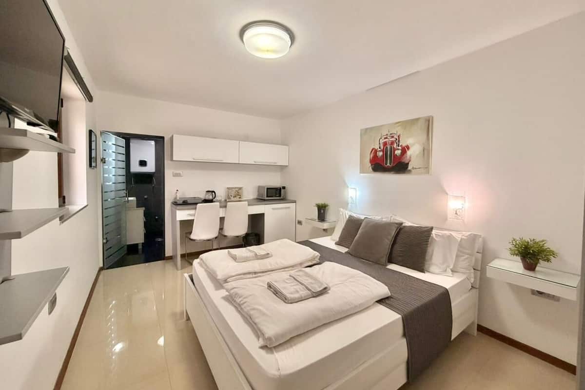 A modern bedroom with a bed, bedside tables, a desk, and a chair.