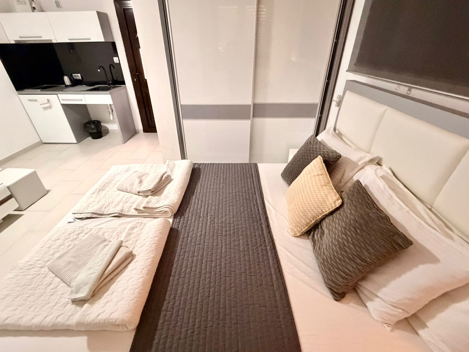 Een moderne hotelkamer met een bed, een klein bureau en een kitchenette.