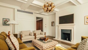 A living room with a sofa, ottoman, and a fireplace. - Mayfair Luxury 3BR at SLO Claridge House (London)