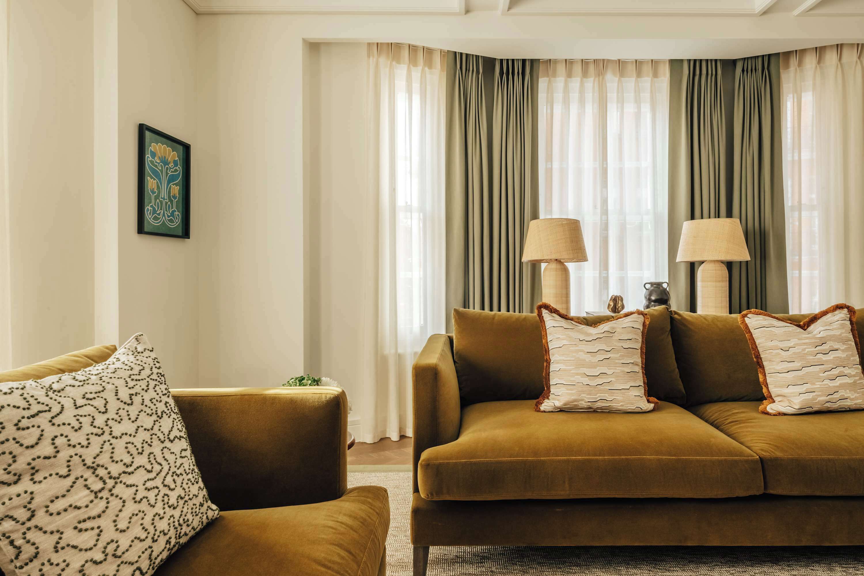 A living room with a brown sofa, two lamps, and a framed artwork on the wall.