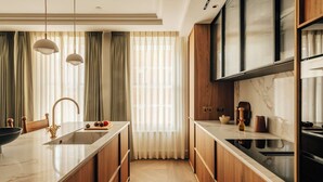 A modern kitchen with wooden cabinets, a marble countertop, and a built-in oven. - Mayfair Luxury 3BR at SLO Claridge House (London)