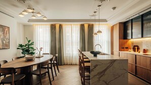 A modern kitchen with a marble island, wooden cabinets, and pendant lighting. - Mayfair Luxury 3BR at SLO Claridge House (London)