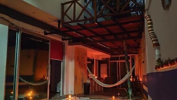 An indoor swimming pool with a wooden ceiling structure, a hammock, and candles. - Cancún Hotel Boutique & Hostel (Cancún)