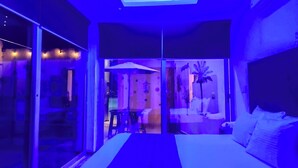 A bedroom with a bed, a glass door leading to a balcony, and a view of the outside. - Cancún Hotel Boutique & Hostel (Cancún)