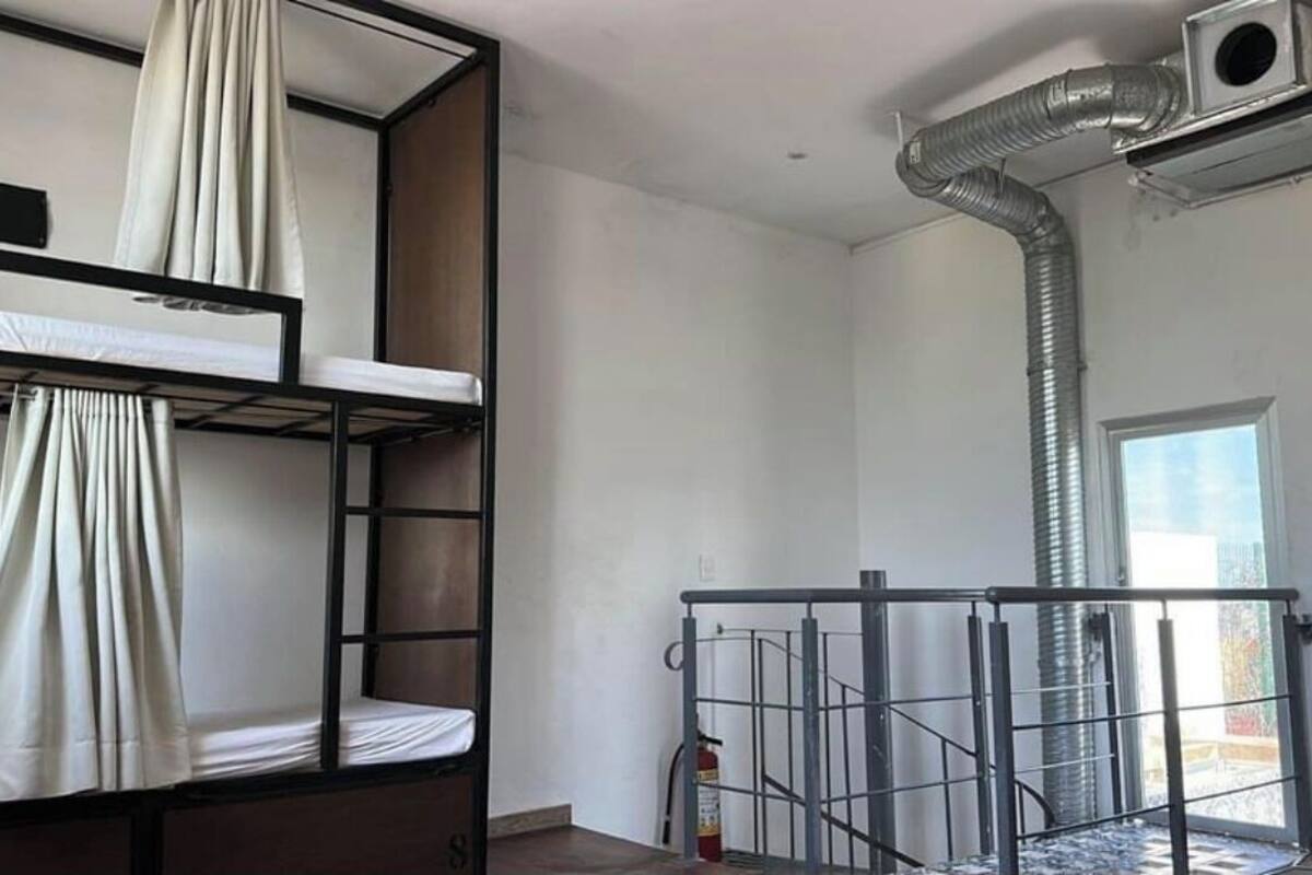 Un dormitorio con literas, una ventana y un equipo de aire acondicionado.