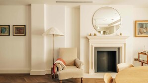 Ein Zimmer mit Kamin, einem runden Spiegel und einer Lampe.