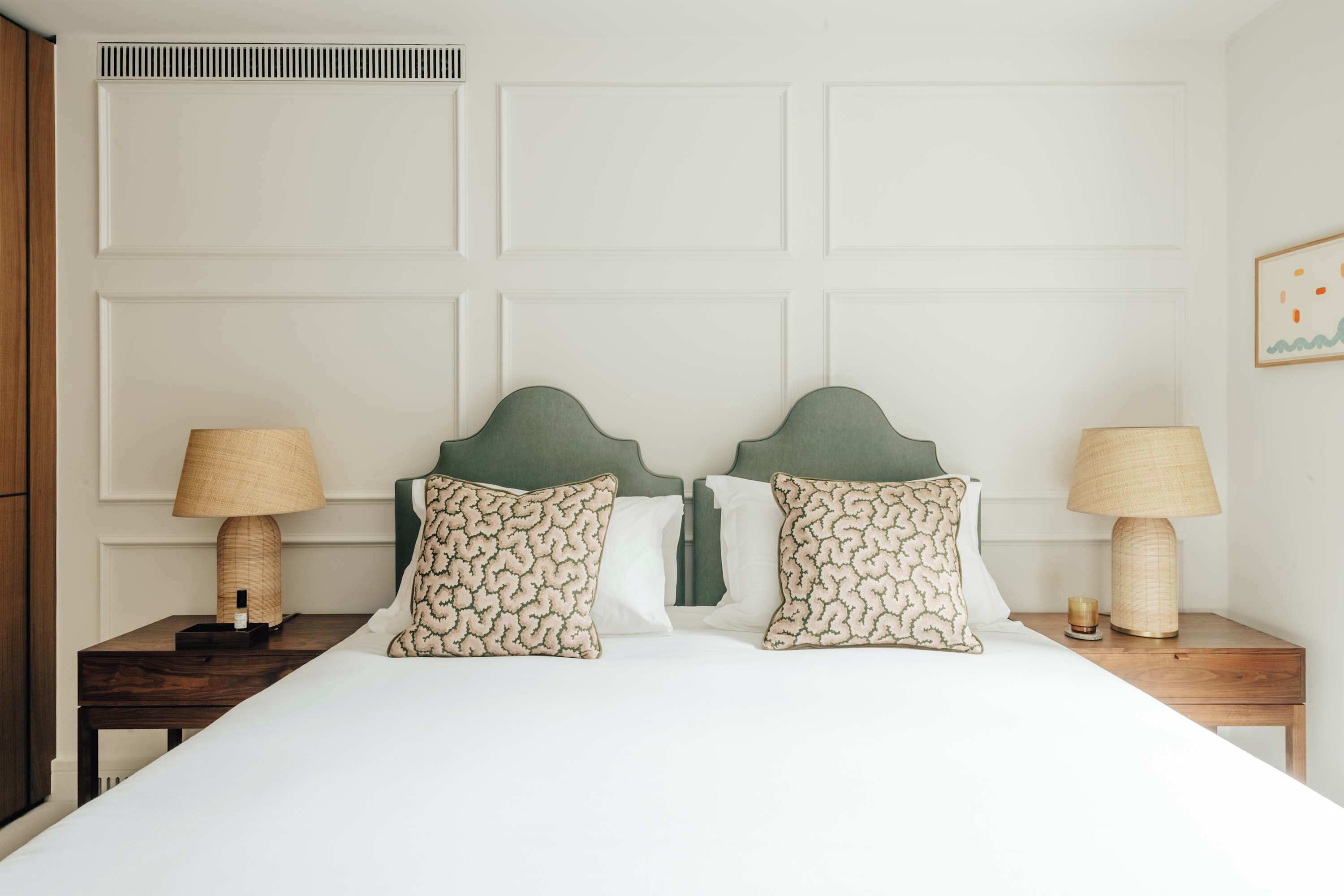 A hotel room with a large bed, two bedside tables, and a headboard.