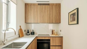A modern kitchen with wooden cabinets, a built-in oven, and a stainless steel sink. - SLO Claridge House: 2BR apartment Mayfair (London)