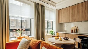 Ein modernes Wohnzimmer mit einer Couch, einem Esstisch und einer Küchenzeile mit Holdekor und einer Marmorarbeitsplatte.