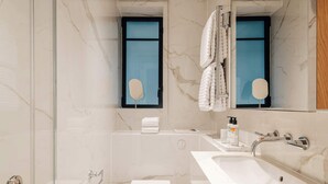 Ein modernes Badezimmer mit Duschkabine aus Glas, einer weißen Toilette, einem Waschbecken mit Spiegel und einem Handtuchhalter.