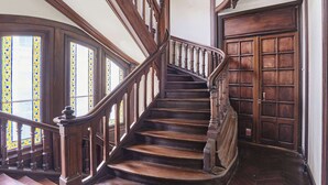 Una escalera de madera con barandillas ornamentales y una gran puerta de madera al final.