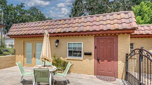 Une maison avec un toit en tuiles, une porte rouge et un petit porche avec une table et des chaises.