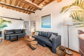 Een woonkamer met een bank, salontafel en lamp.