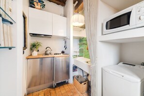 Una cucina compatta con elettrodomestici in acciaio inox, un piano di lavoro in legno e un lampadario.