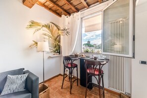 Una habitación acogedora con sofá, dos sillones, una mesita, una planta, una lámpara y una ventana con vistas.