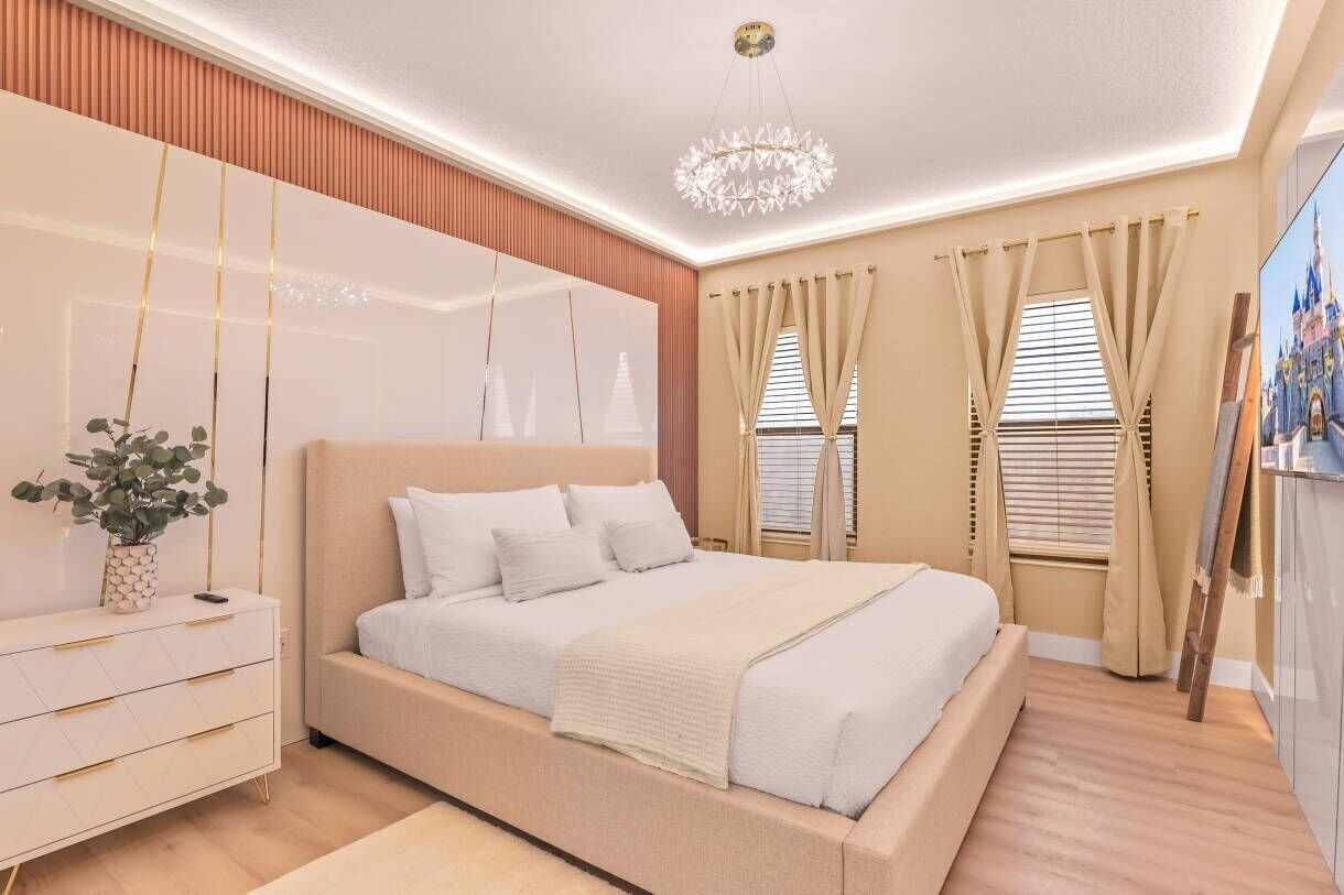 A modern bedroom with a large bed, a bedside table, a hanging plant, and a painting on the wall.